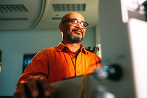 man in orange shirt looking at computer